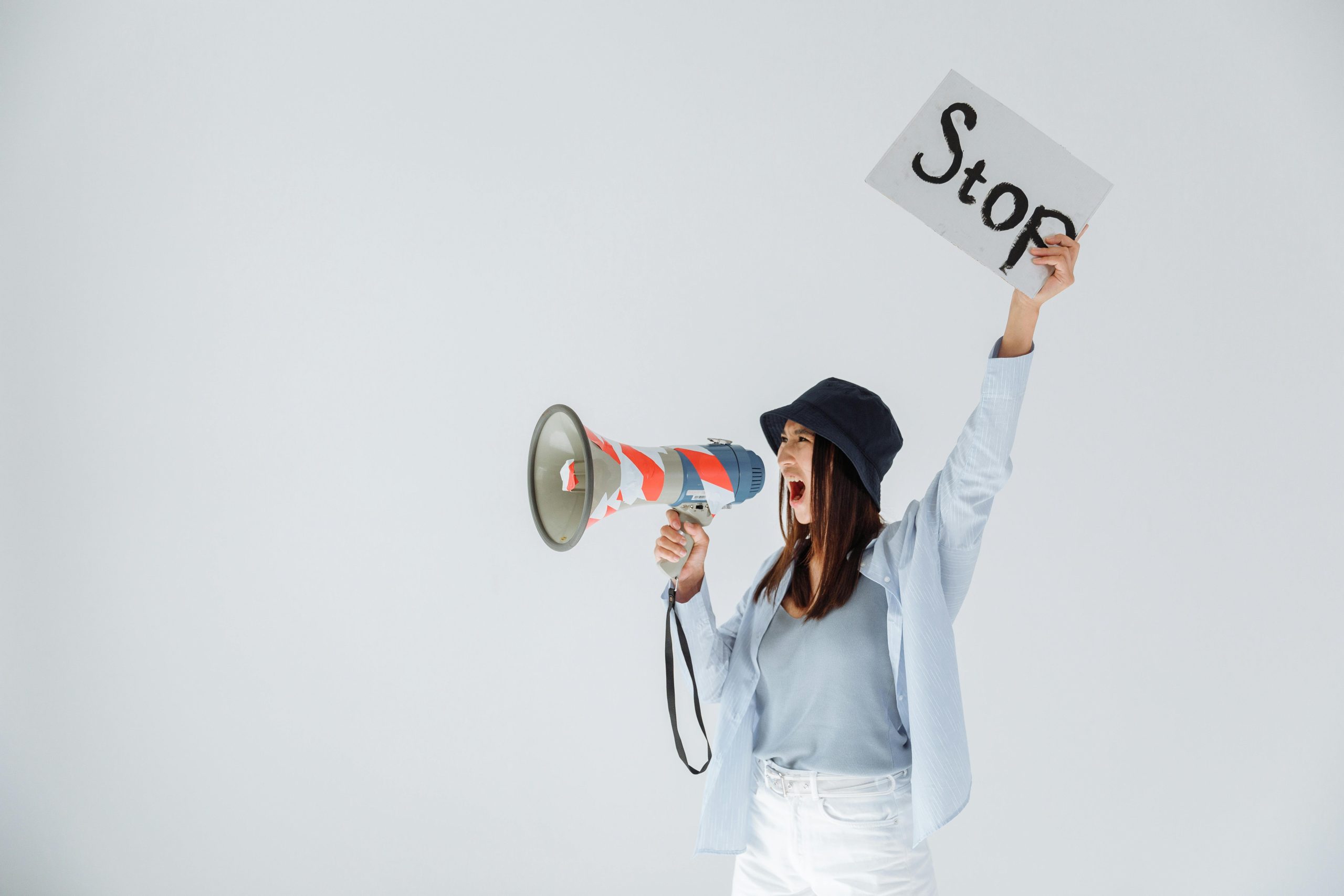 A woman holding a megaphone and a sign that says “Stop,” shouting with determination—symbolizing the act of reclaiming one’s voice and setting boundaries.