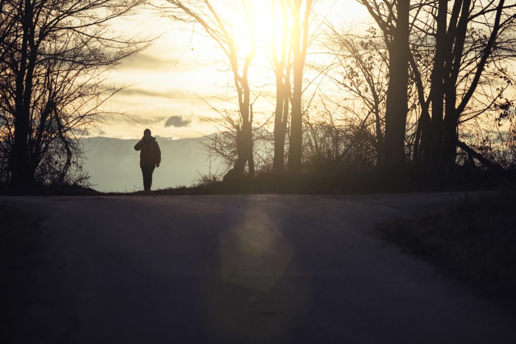 Person walking forward through soft evening light, symbolizing the uncertainty and possibility that come with life transitions and personal growth.