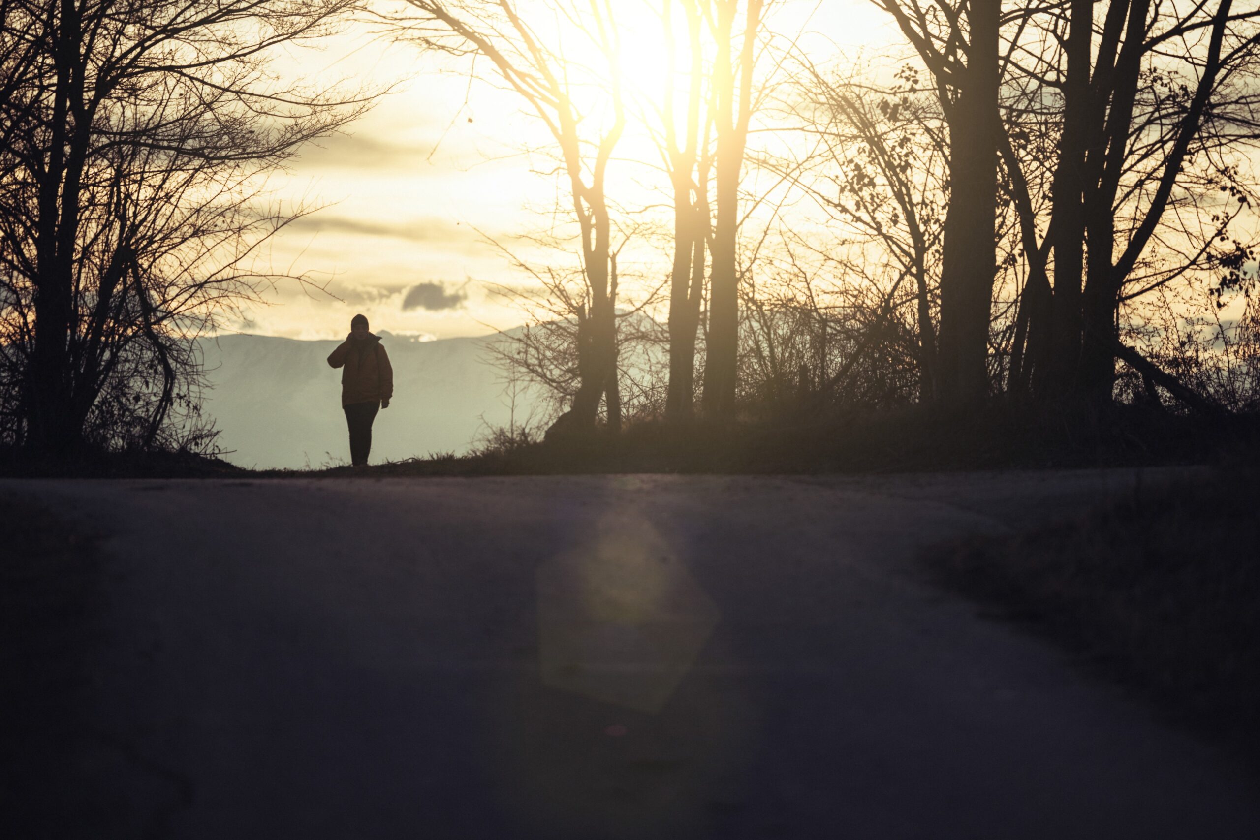 Person walking forward through soft evening light, symbolizing the uncertainty and possibility that come with life transitions and personal growth.