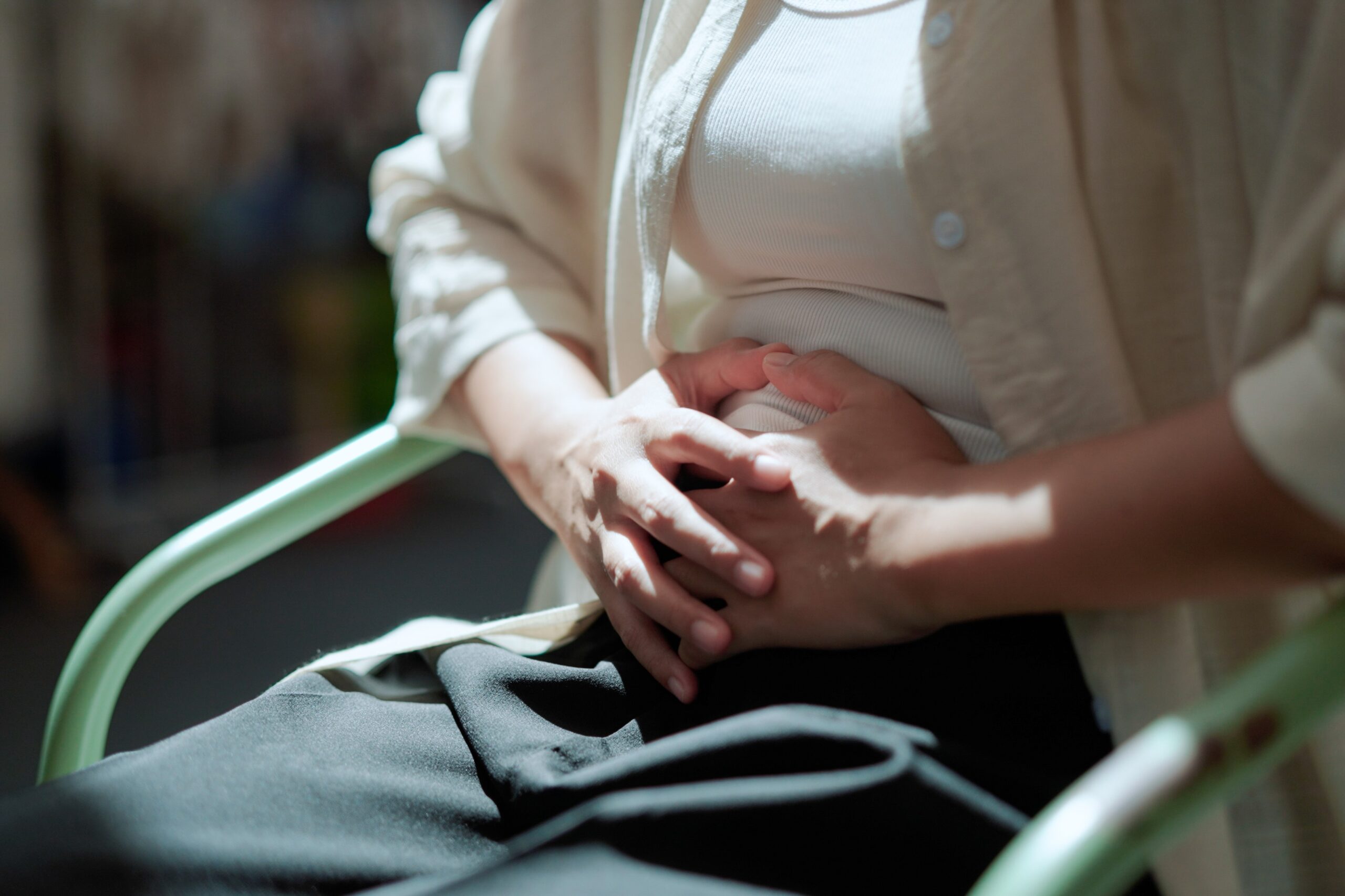 Person gently placing a hand on their body, reflecting how anxiety shows up through nervous system sensations.