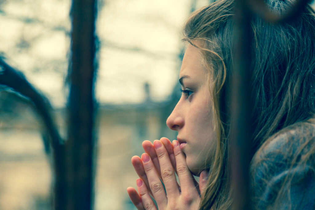 Woman sitting quietly by a window with soft natural light, reflecting chronic tension and difficulty relaxing.