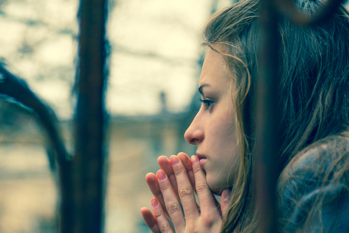 Woman sitting quietly by a window with soft natural light, reflecting chronic tension and difficulty relaxing.