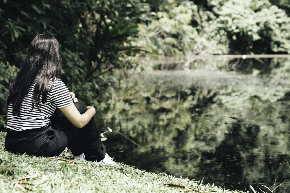 Woman sitting quietly alone in reflection, representing anxiety, overthinking, and nervous system overwhelm